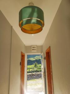 a large green light hanging from a ceiling with a window at Purple Mountain Cottage in Killarney