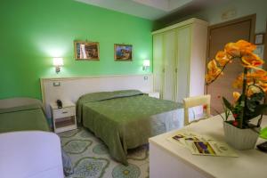 a green bedroom with a bed and a table at Hotel Rivamare in Ischia