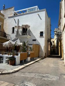 a white building with tables and chairs in a street at CasUccia, nel cuore del centro storico di Gallipoli in Gallipoli