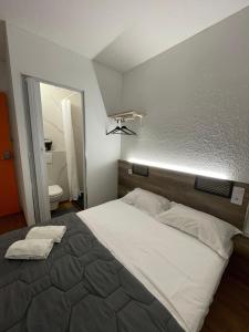 a bedroom with a large bed and a mirror at HOTEL THANIA Sète Frontignan in Frontignan