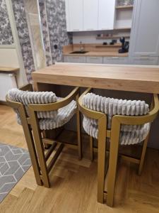 Una cocina con una mesa de madera y dos sillas. en Ultra-central apartament Kogălniceanu, en Oradea