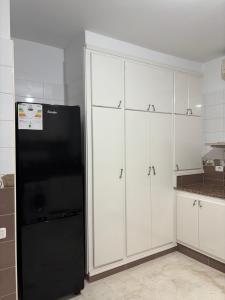 a kitchen with white cabinets and a black refrigerator at Appartement haut standing 170 m2 in Tunis
