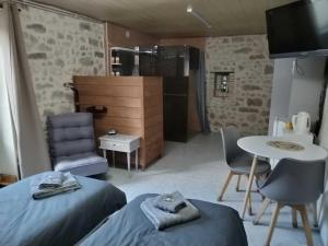 a room with two beds and a table and a kitchen at Gîte du Gardoir in Boresse-et-Martron