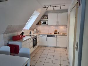 a small kitchen with white cabinets and white appliances at Kattenwarft OG in Böhl