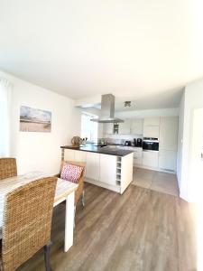 a kitchen with white cabinets and a table and chairs at Haus Lieblingsquartier in Tating