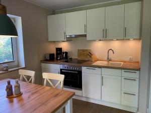 una cucina con mobili bianchi e un tavolo di legno di Wohnung Wiesenblick Whg 1 a Böhl