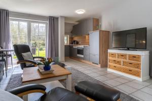 un salon avec une télévision et une cuisine dans l'établissement Auszeit unter Reet, à Böhl