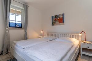 une chambre avec un lit avec des draps blancs et une fenêtre dans l'établissement Auszeit unter Reet, à Böhl