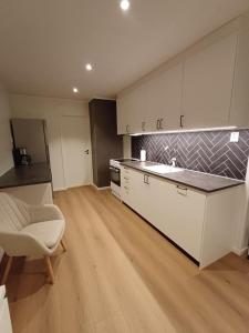 a kitchen with white cabinets and a sink and a chair at Private 4 bedroom getaway in Lofoten in Vestvågøya