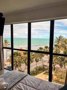 a bedroom with a view of the beach and the ocean at Residencial Loft - Studio -407 in Maceió +7 photos