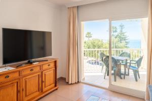 a living room with a flat screen tv and a balcony at Apartamentos Solset Nerja in Nerja