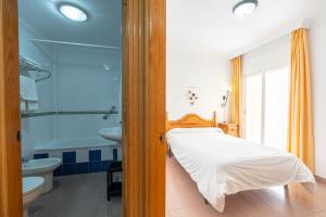 a bedroom with a bed and a tub and a sink at Apartamentos Solset Nerja in Nerja