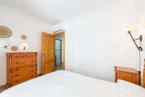 a bedroom with a white bed and a wooden dresser at Apartamentos Solset Nerja in Nerja