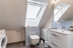 a bathroom with a toilet and a sink and a window at Haus Eismöwe in Böhl
