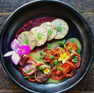 a black plate of food with vegetables and bread at Renacer in Termales - agua caliente - nuqui +21 photos