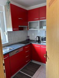 a red kitchen with black counter tops and appliances at Apartman M&M Osijek in Osijek