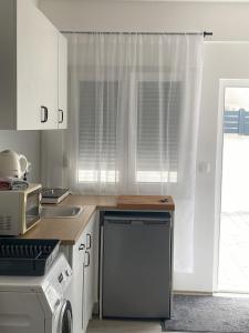 a kitchen with white cabinets and a sink and a window at Apartman Zeljka in Pula +3 photos