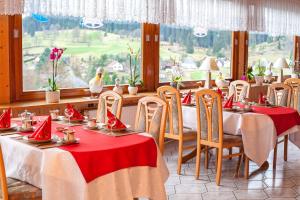 Waldhotel Auerhahn B&B Bed & Breakfast في إيسينباخ: غرفة طعام مع طاولات وكراسي بمناديل حمراء
