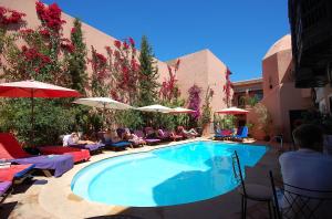 una piscina con personas sentadas en sillas y sombrillas en Les Borjs De La Kasbah, en Marrakech