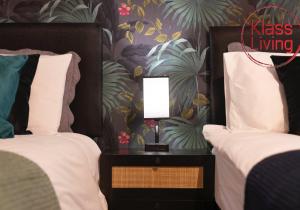 a bedroom with two beds and a lamp on a night stand at Colt Apartment by Klass Living Coatbridge in Glenboig