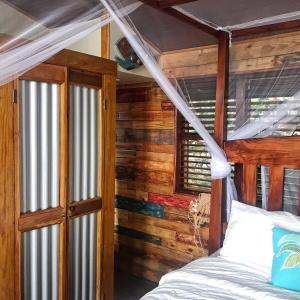ein Schlafzimmer mit einem Bett und einer Holzwand in der Unterkunft Treehouse Hideaway Villa I - Piton and Ocean Views in Soufrière