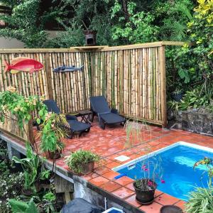 eine Terrasse mit zwei Stühlen und einem Swimmingpool in der Unterkunft Treehouse Hideaway Villa I - Piton and Ocean Views in Soufrière