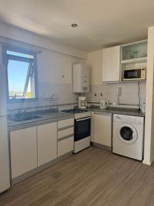 a kitchen with white cabinets and a washer and dryer at Departamento de un dormitorio - FRANCIA in Santa Fe