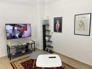 a living room with a tv and a white wall at Ermes Center Apartment in Elbasan