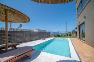 a swimming pool with an umbrella next to a house at Diosa Luxury Living with Private Pool in Lygaria