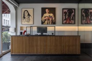 a lobby with a wooden reception desk with pictures on the wall at Hotel Pilar in Antwerp +86 photos