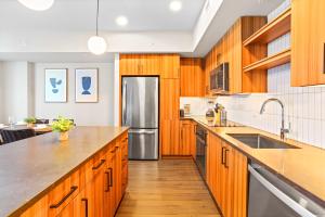 Una cocina con gabinetes de madera y un refrigerador de acero inoxidable. en Comfy Clarendon Apt - Steps from Metro, en Arlington
