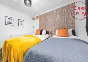 two beds in a bedroom with yellow and gray sheets at Fraser House by Klass Living Rutherglen in Glasgow