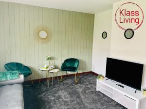 a living room with a flat screen tv and two chairs at Elmbank Avenue House by Klass Living Uddingston in Uddingston
