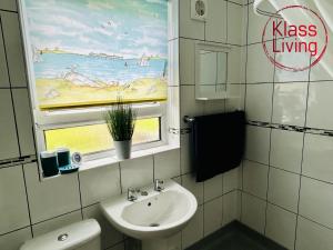 a bathroom with a sink and a window with a painting at Elmbank Avenue House by Klass Living Uddingston in Uddingston