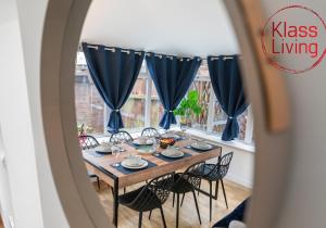 a dining room table with chairs and blue drapes at Fraser House by Klass Living Rutherglen in Glasgow