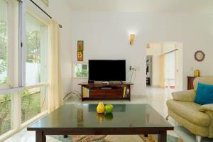 sala de estar con mesa de centro y TV en Villa Bella Vista, Candolim, en Candolim