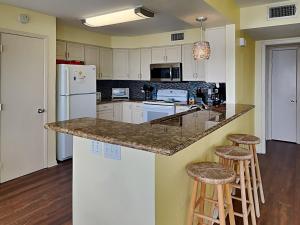 a kitchen with white cabinets and a counter with stools at Whispering Sands Beachfront in Galveston +19 photos