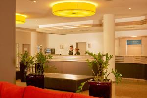 a man and a woman standing at the counter of a salon at H+ Hotel Leipzig-Halle in Landsberg OT Peißen