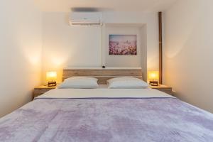 a bedroom with a large bed with two lamps at Anabella in Martinšćica