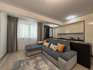 Una sala de estar con un sofá y una cocina. en LuxeVibe Apartments near Mall Moldova, en Iaşi
