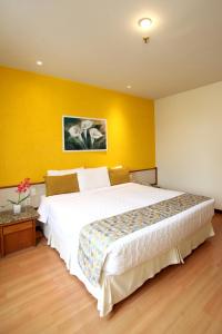 a bedroom with a large bed and a yellow wall at Mengo Palace Hotel in Rio de Janeiro
