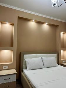 a bedroom with a bed with lights on the wall at Korca Apartment in Korçë