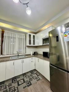a kitchen with white cabinets and a stainless steel refrigerator at Korca Apartment in Korçë +7 photos