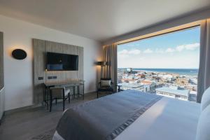 una camera d'albergo con un letto grande e una grande finestra di Hotel Cabo De Hornos a Punta Arenas