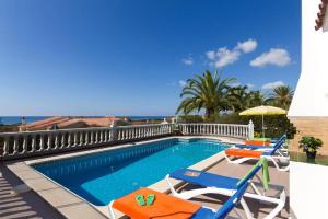 a swimming pool with two chairs and an umbrella at Villa Girasol by Villa Plus in Alaior