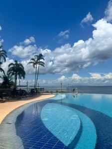 a swimming pool next to a beach with palm trees at Flat Tropical in Manaus