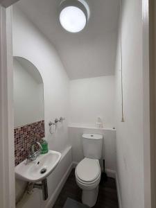 a white bathroom with a toilet and a sink at Chelmsford 5 Bedroom Large House with Garden & Parking in Chelmsford
