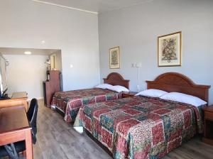Una habitación de hotel con dos camas y un escritorio. en Welcome Inn and Suites, en Saint Johns
