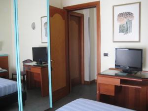 una camera d'albergo con TV su una scrivania con un letto di Hotel Soraya a San Benedetto del Tronto