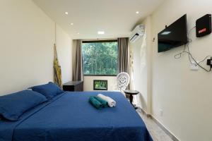 a bedroom with a blue bed and a television at St Luxo Copacabana Beach and Metro in Rio de Janeiro